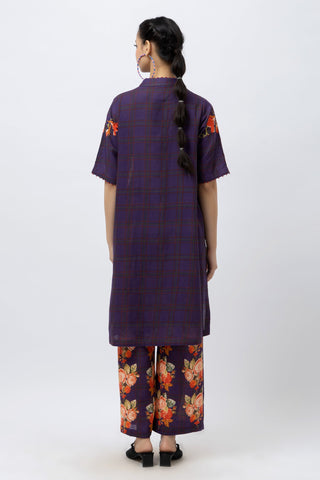 Person wearing a purple outfit with floral patterns on a white background