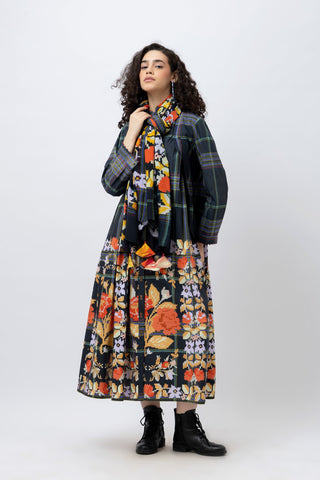 Woman wearing a floral dress, plaid coat, and black boots on a white background