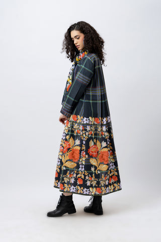 Woman wearing a plaid coat over a floral dress on a white background